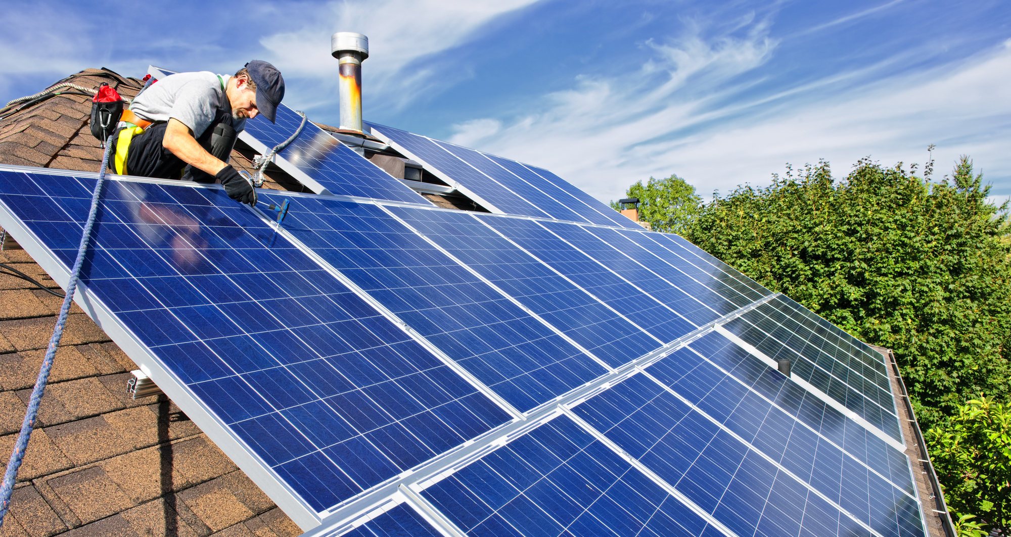Man installing alternative energy photovoltaic solar panels on roof